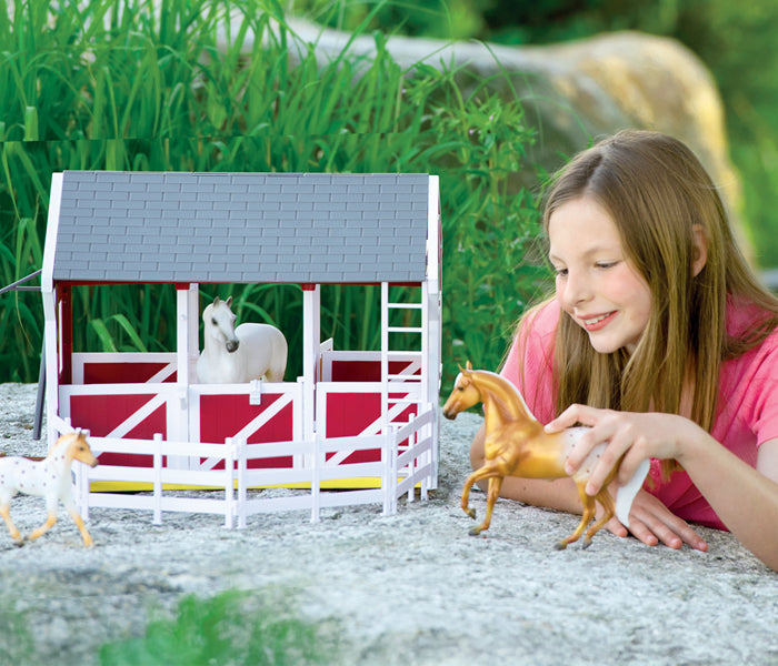 A child playing with Breyer model horses and a barn