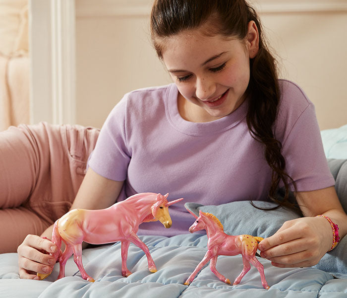 A child on a bed playing with Breyer's Candy Delights models