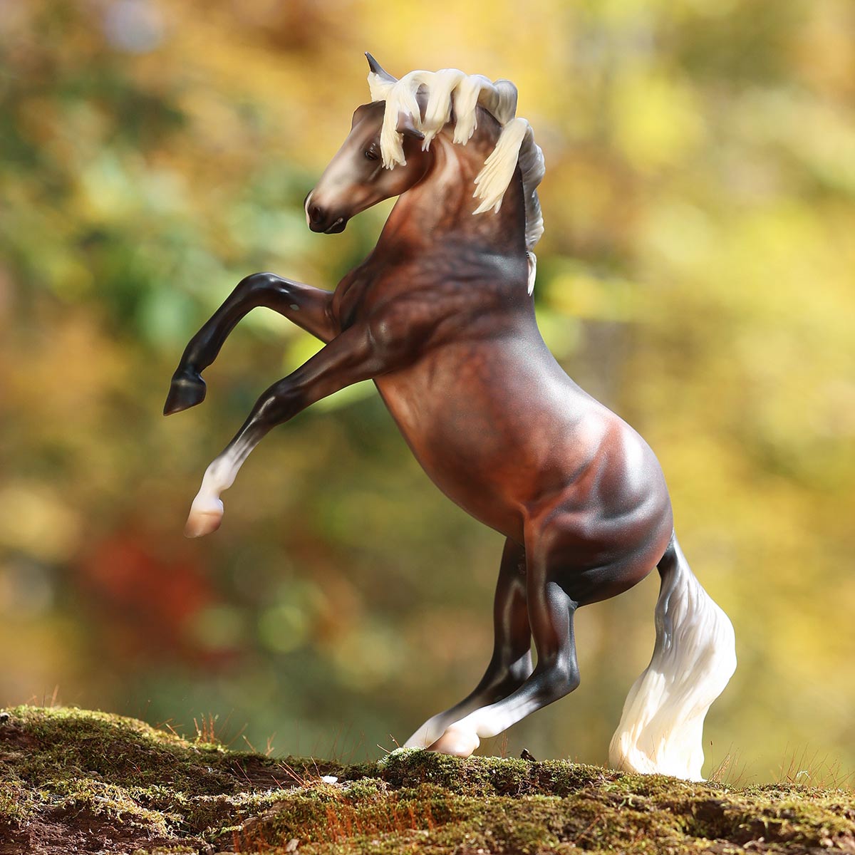 A Breyer Premier Model rearing on a moss covered mound