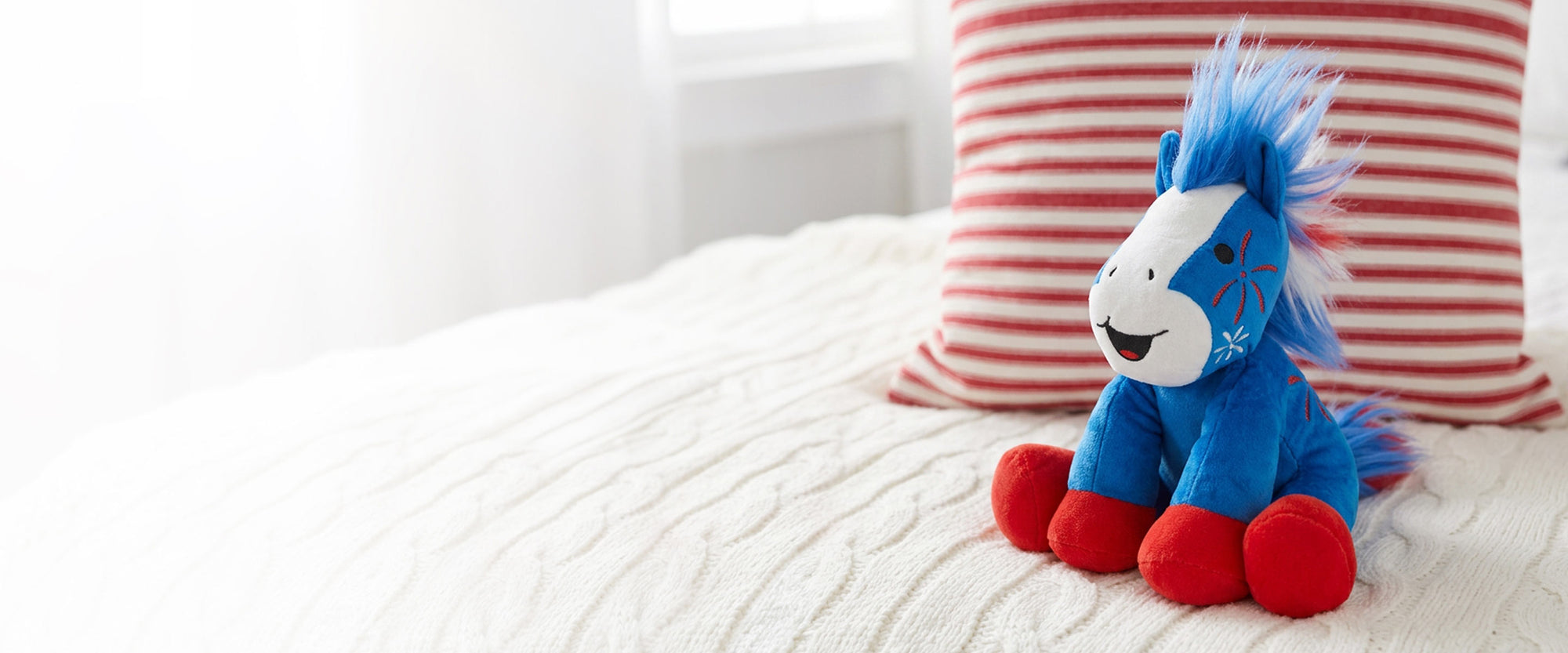 Boom | 2026 Americana Plush sitting on a bed