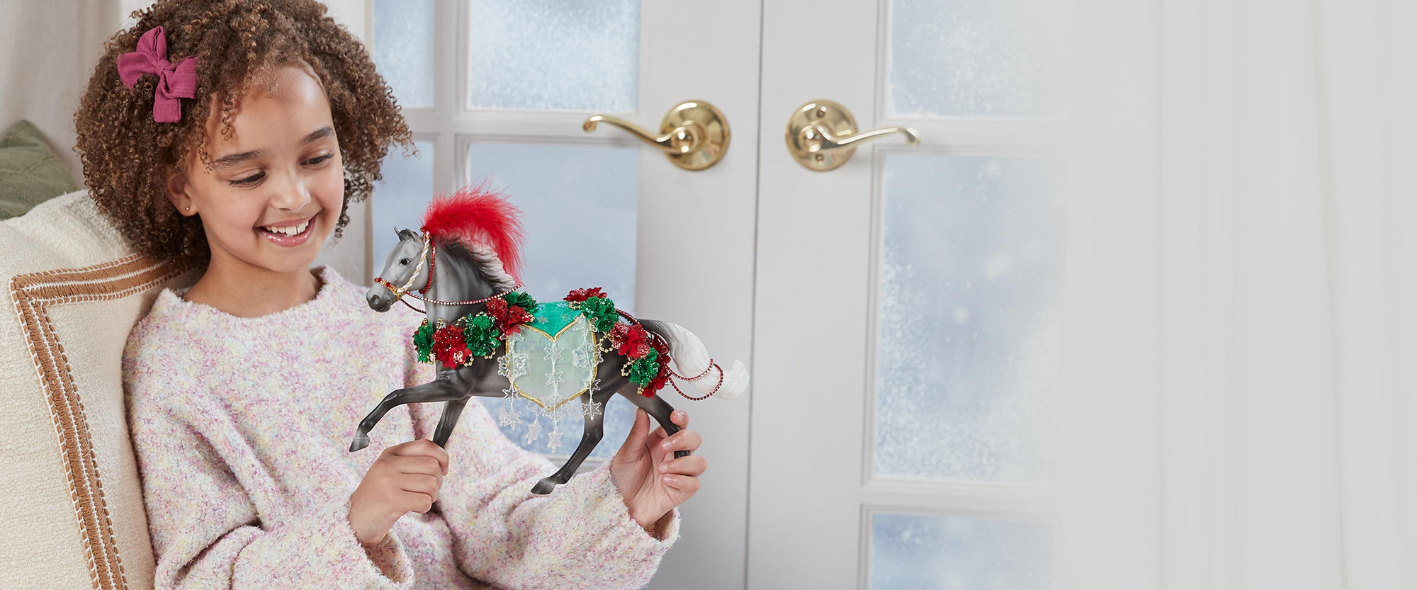 A girl playing with the 2025 Breyer Holiday Horse - Christmas in Bloom