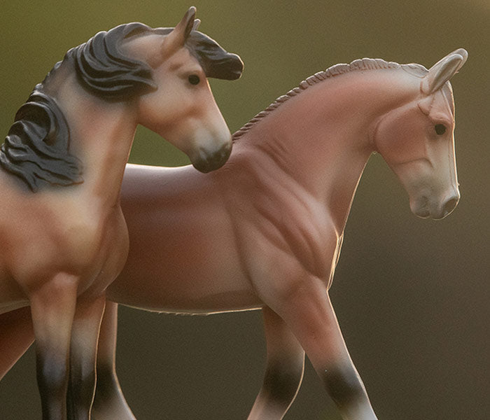 Two Breyer Stablemates standing side-by-side on a a natural green background