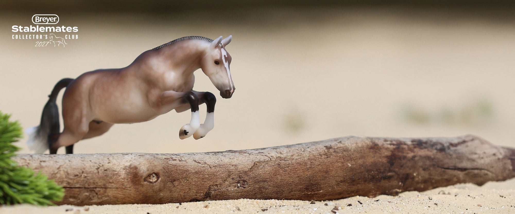 Luca - A 2027 Stablemates Club release shown jumping over a log  and the Stablemates Club logo in he background