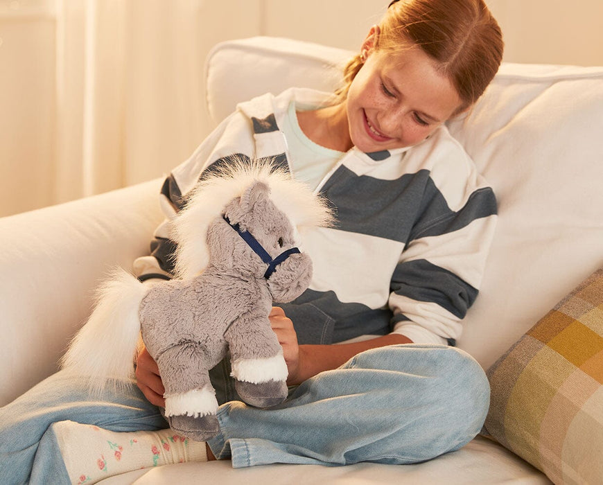 A child holding the 11" Grey Horse | Bridle Buddies sitting o a couch