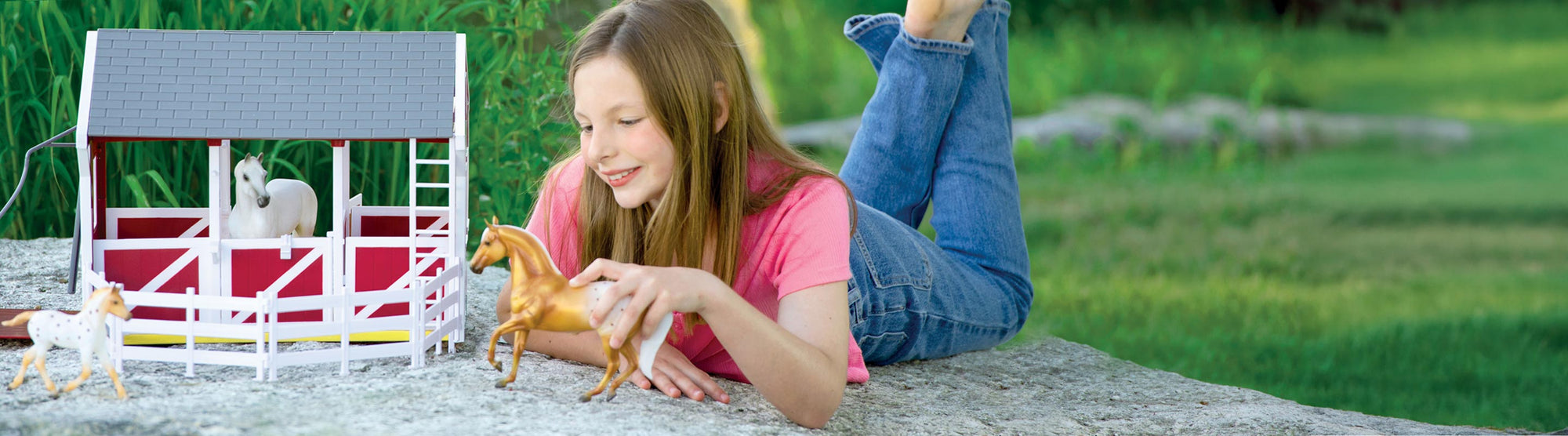 A child playing with Breyer model horses and a barn