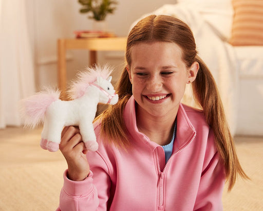 A child holding up the 7" Unicorn | Whinny Bits in front of a couch