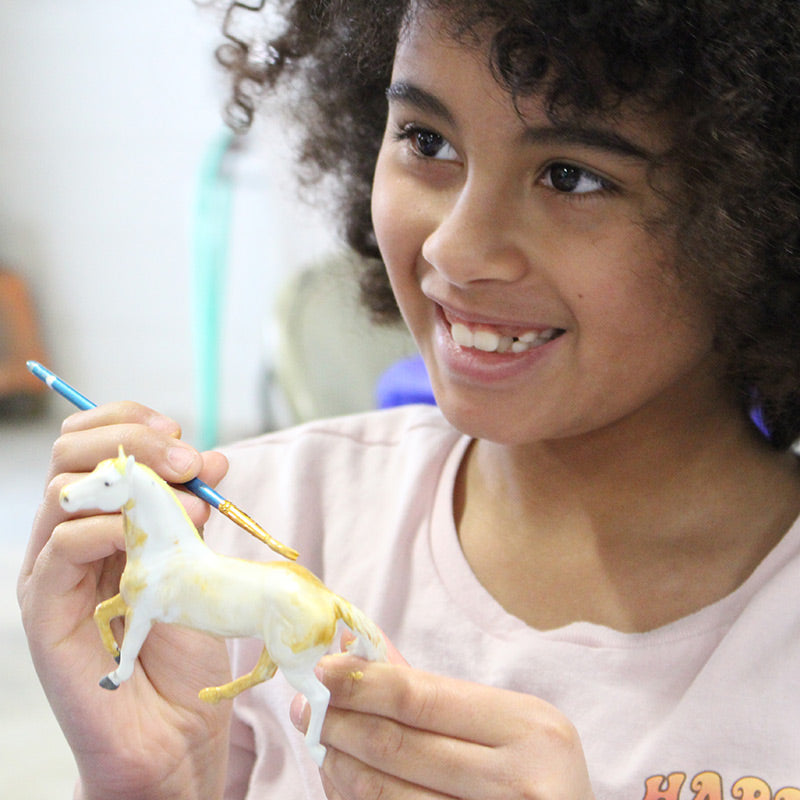 A child painting a Stablemate at a Breyer event