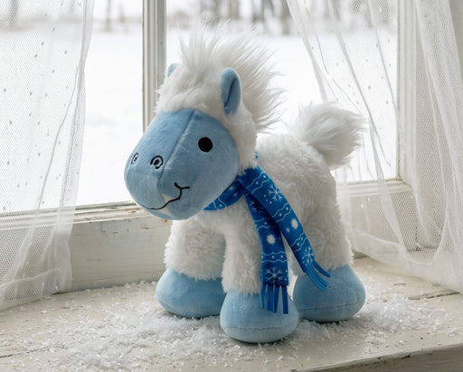 Blizzard | 2026 Holiday Plush with blue scarf on a window seat with snow in the background facing left 