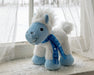 Blizzard | 2026 Holiday Plush with blue scarf on a window seat with snow in the background facing left 