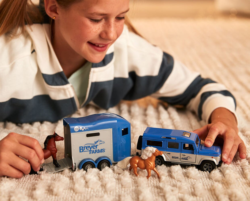 A child playing with the Breyer Farms™ Land Rover® and Tag-A-Long Horse Trailer on the floor