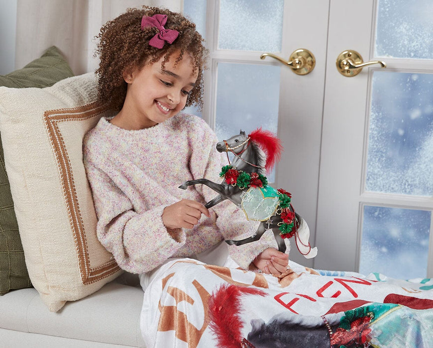 a child playing with the Christmas in Bloom | 2025 Holiday Horse on a chair