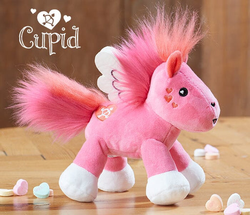 Cupid | Valentine’s Day Plush standing an a table with heart shaped candy