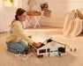 A Girl playing with the Deluxe Arena Stable on a floor with the roof open - putting the roof back on