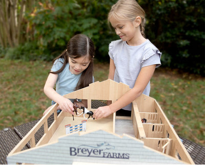 Two girls playing with the Deluxe Arena Stable - with the roof off