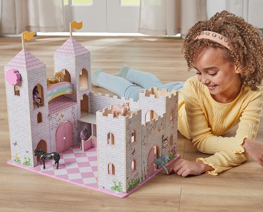 A child playing with the Unicorn Magic Deluxe Wood Castle Playset on a wooden floor in a house