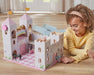 A child playing with the Unicorn Magic Deluxe Wood Castle Playset on a wooden floor in a house