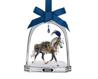 Snowbird | Stirrup Ornament Model Breyer. A miniture Snowbird in a stirrup with a blue gem on a white background