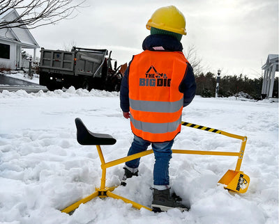 The Big Dig in the snow with a child wearing a Big Dig helmet and vest with a truck in the background
